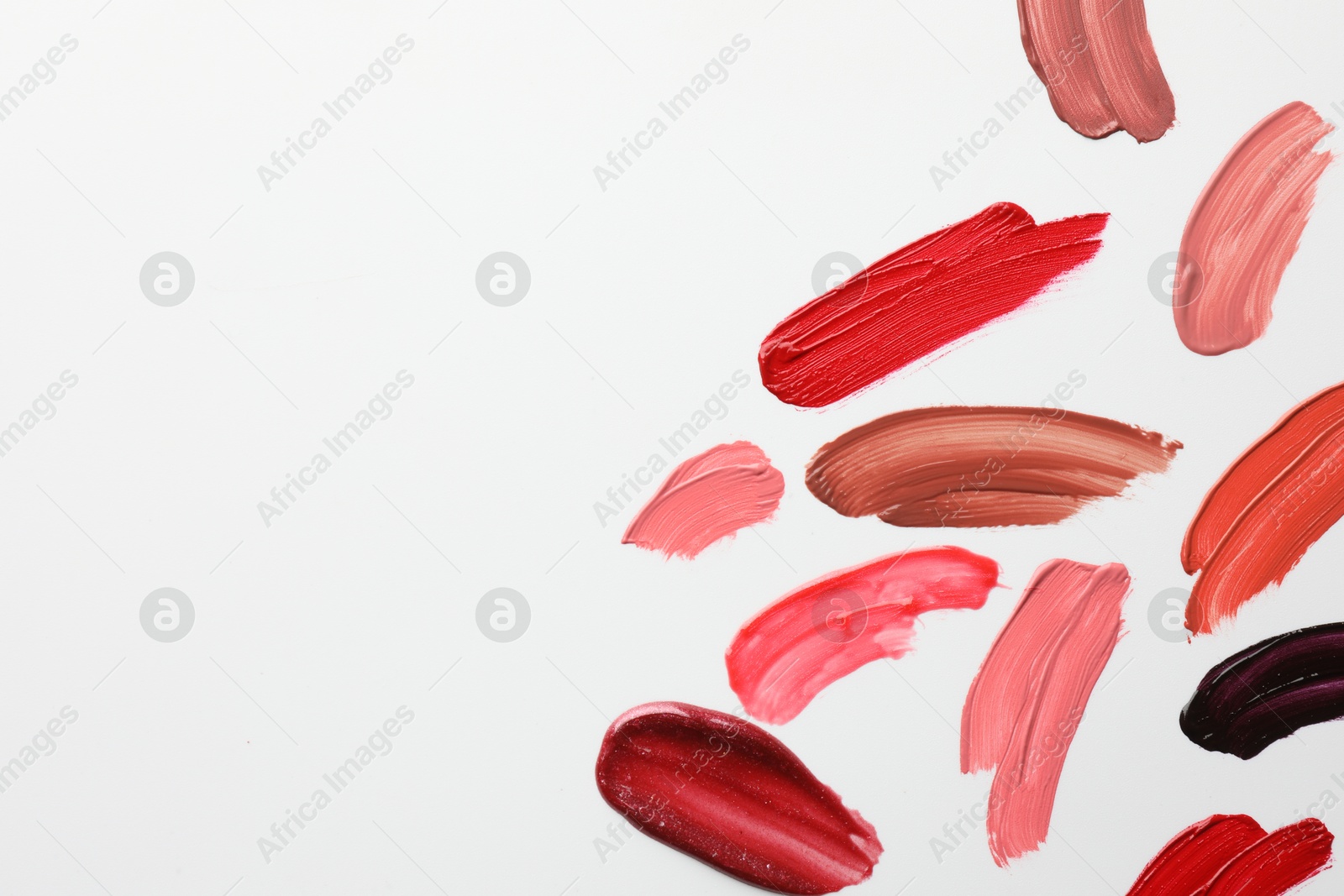 Photo of Smears of different lip products on white background, top view