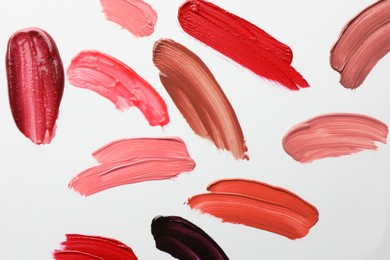 Photo of Smears of different lip products on white background, top view