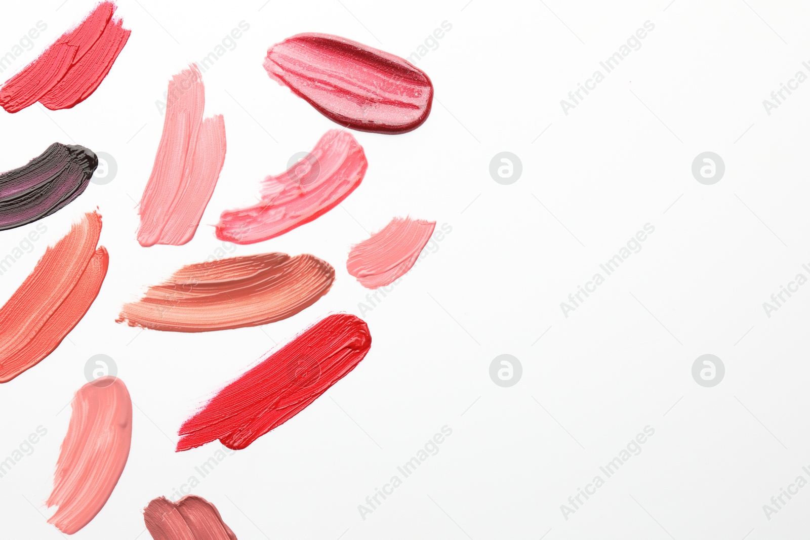 Photo of Smears of different lip products on white background, top view