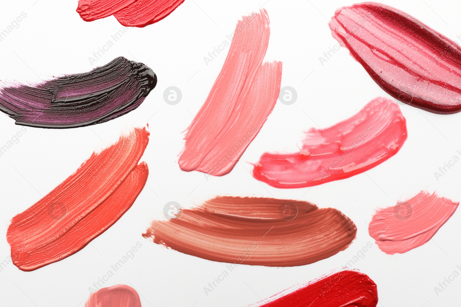 Photo of Smears of different lip products on white background, top view