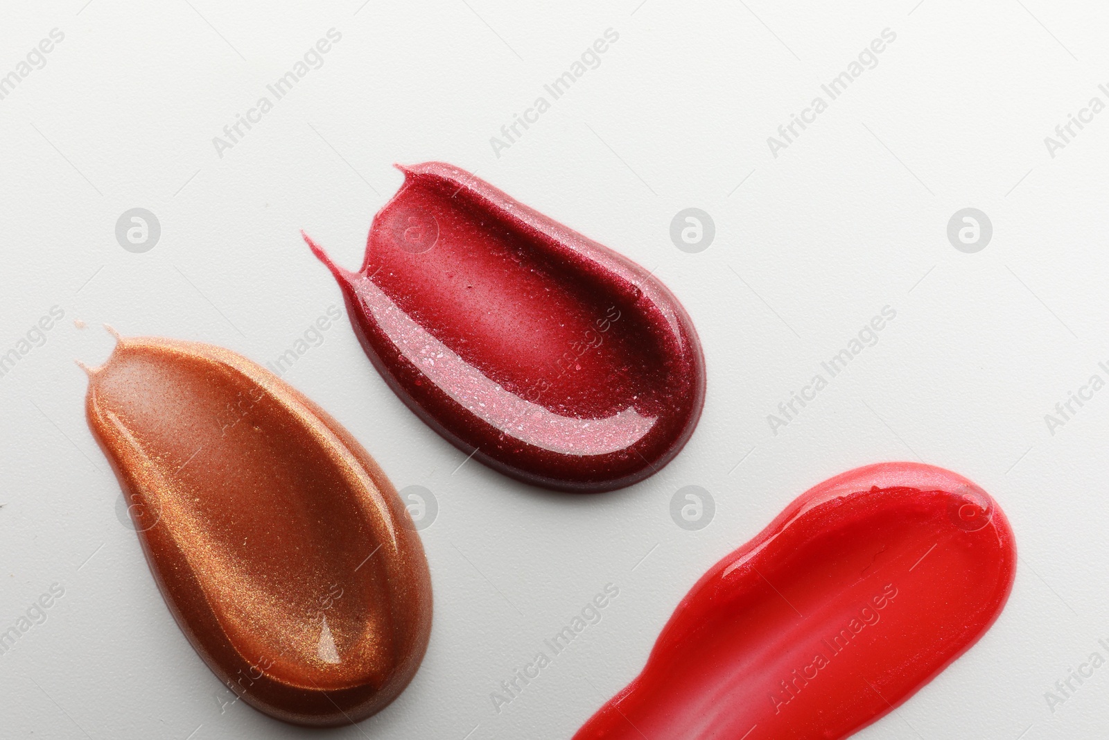 Photo of Smears of different lip products on white background, top view