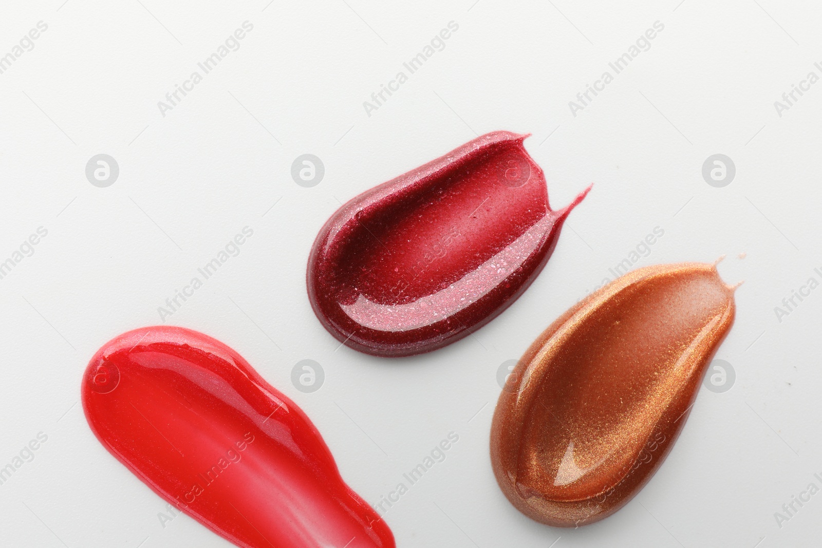 Photo of Smears of different lip products on white background, top view