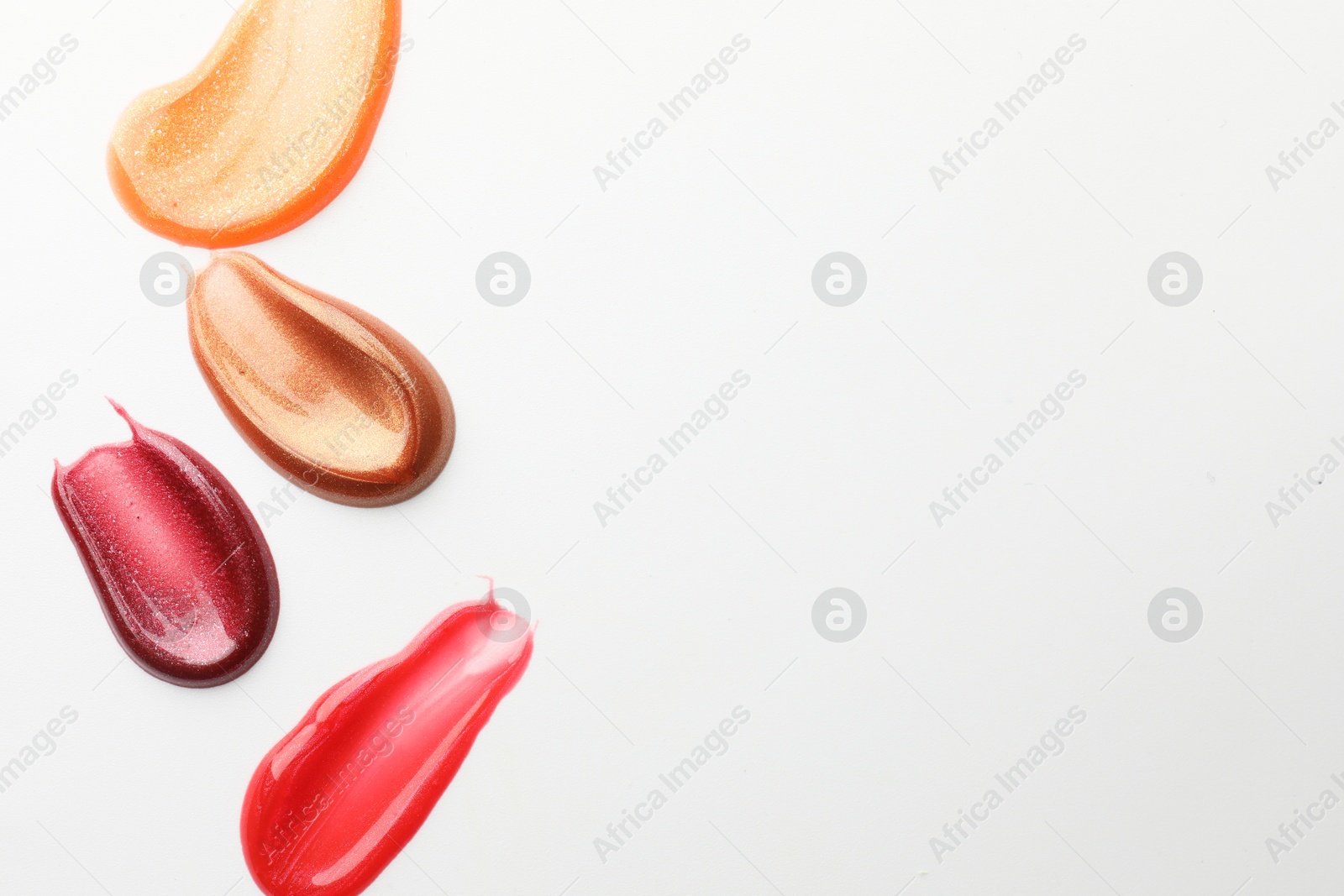 Photo of Smears of different lip products on white background, top view