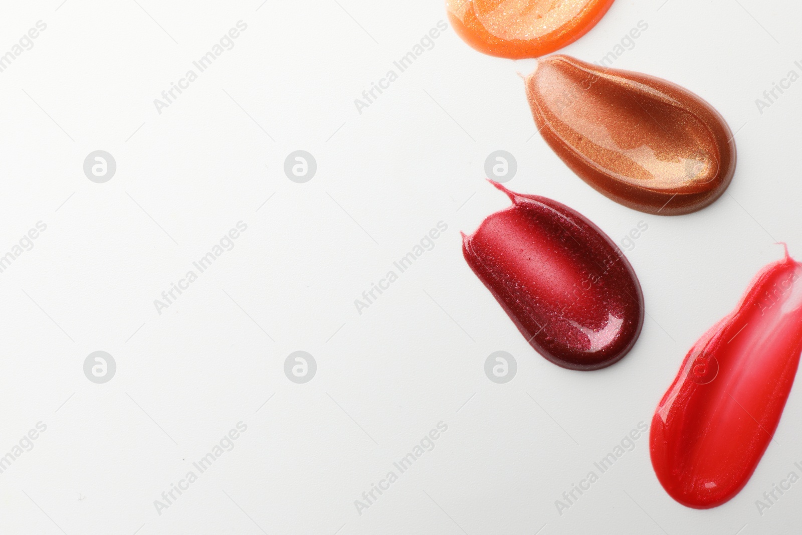 Photo of Smears of different lip products on white background, top view