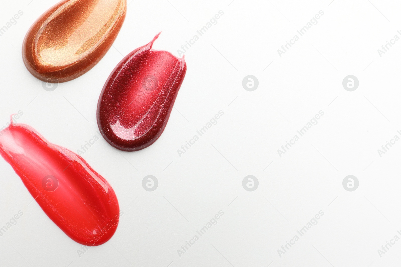 Photo of Smears of different lip products on white background, top view