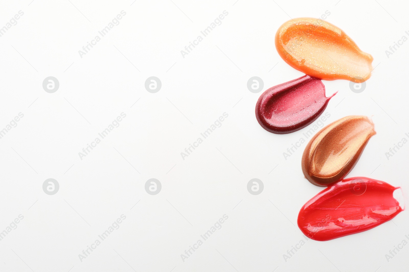 Photo of Smears of different lip products on white background, top view