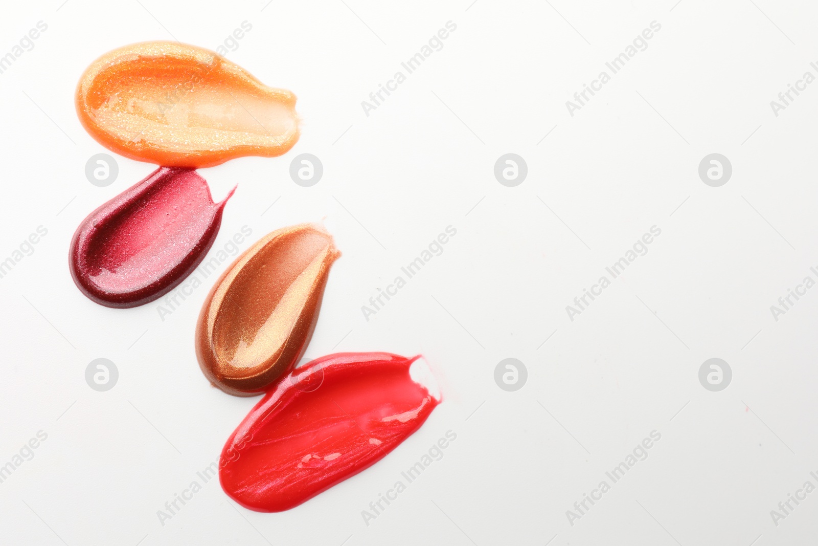 Photo of Smears of different lip products on white background, top view