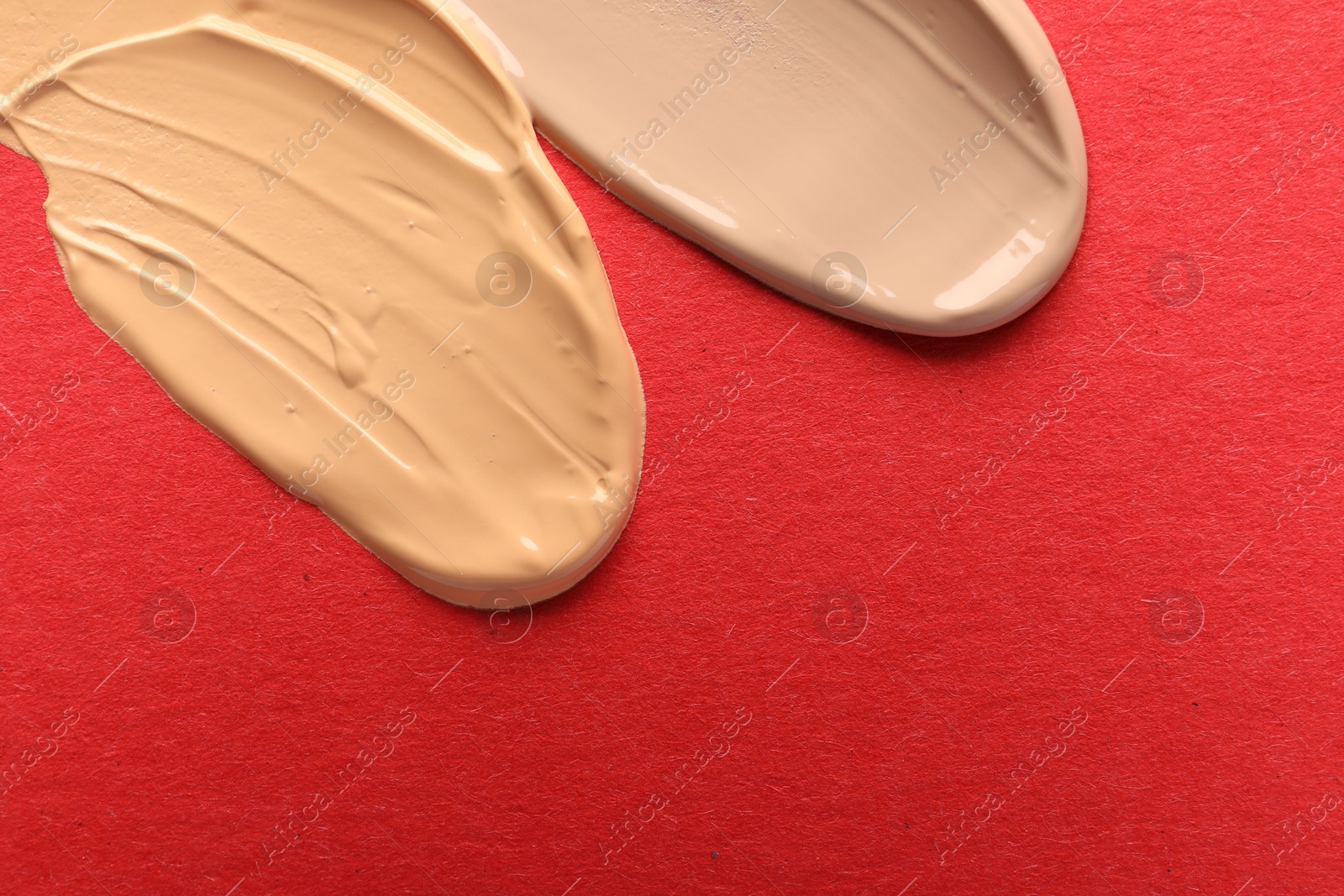 Photo of Samples of different foundations on red background, top view. Space for text