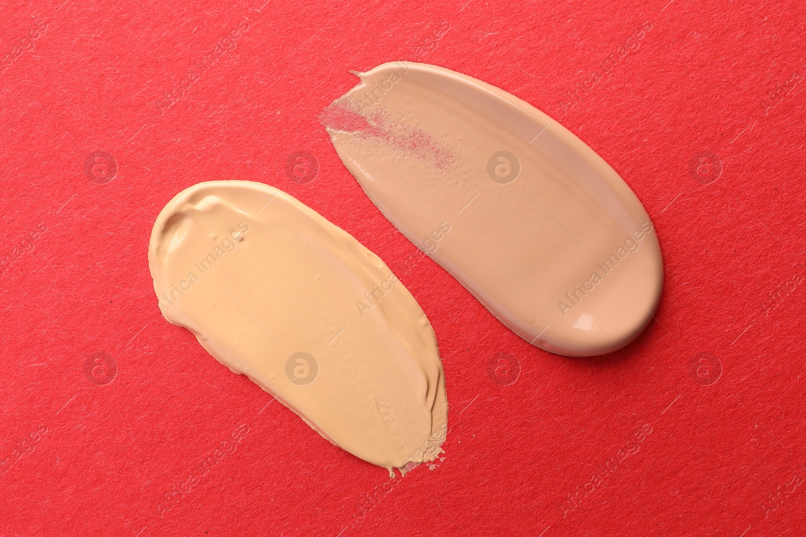 Photo of Samples of different foundations on red background, top view