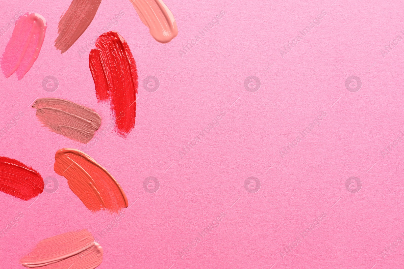 Photo of Samples of different lip products on pink background, top view. Space for text