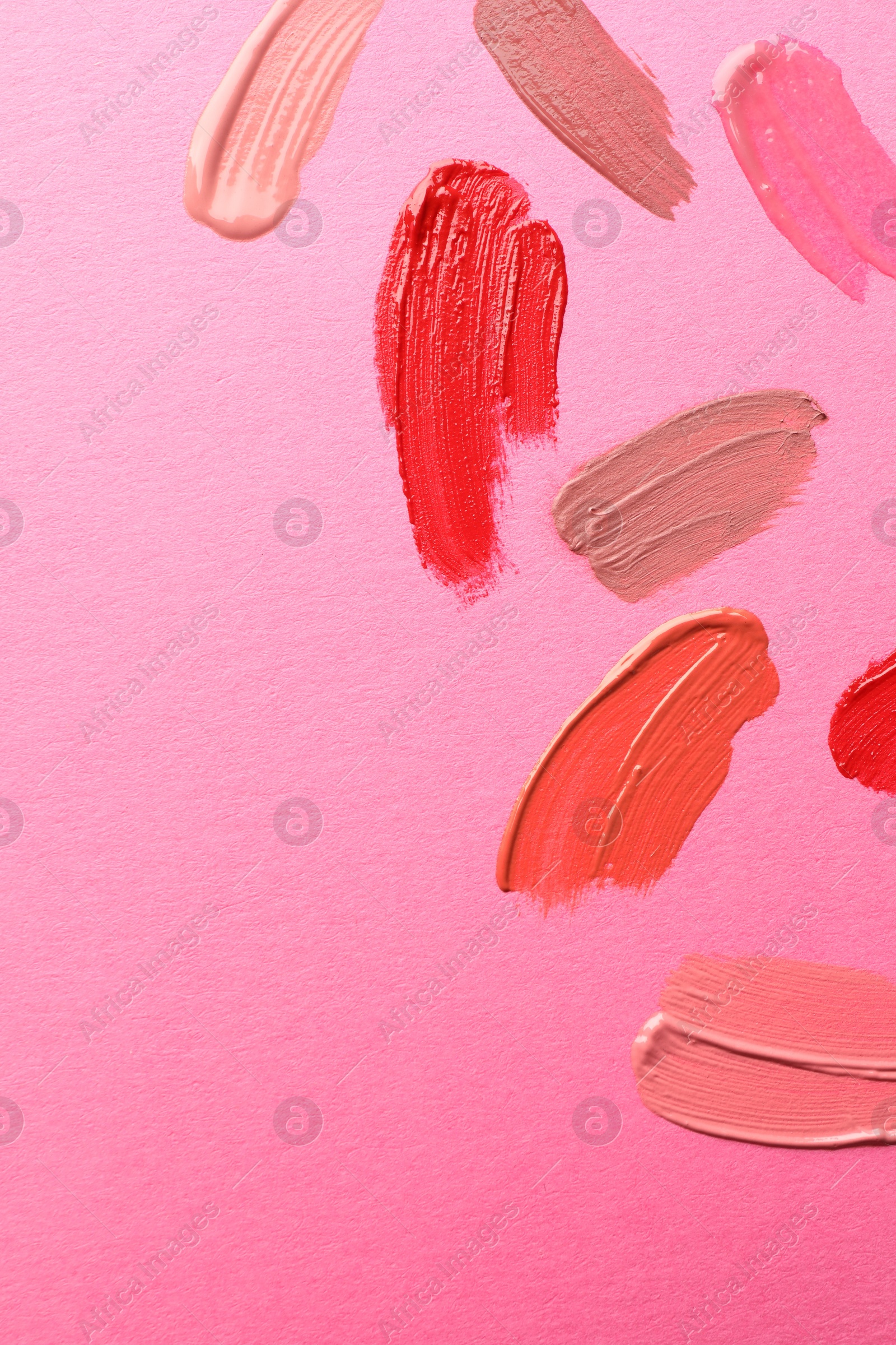 Photo of Samples of different lip products on pink background, top view. Space for text