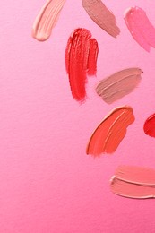 Samples of different lip products on pink background, top view. Space for text