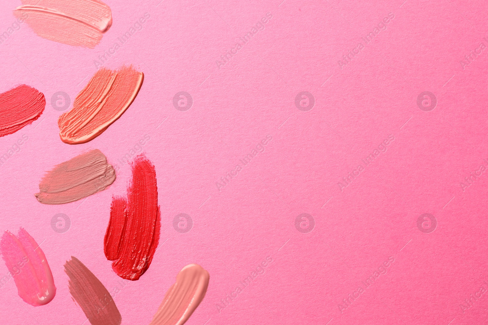 Photo of Samples of different lip products on pink background, top view. Space for text