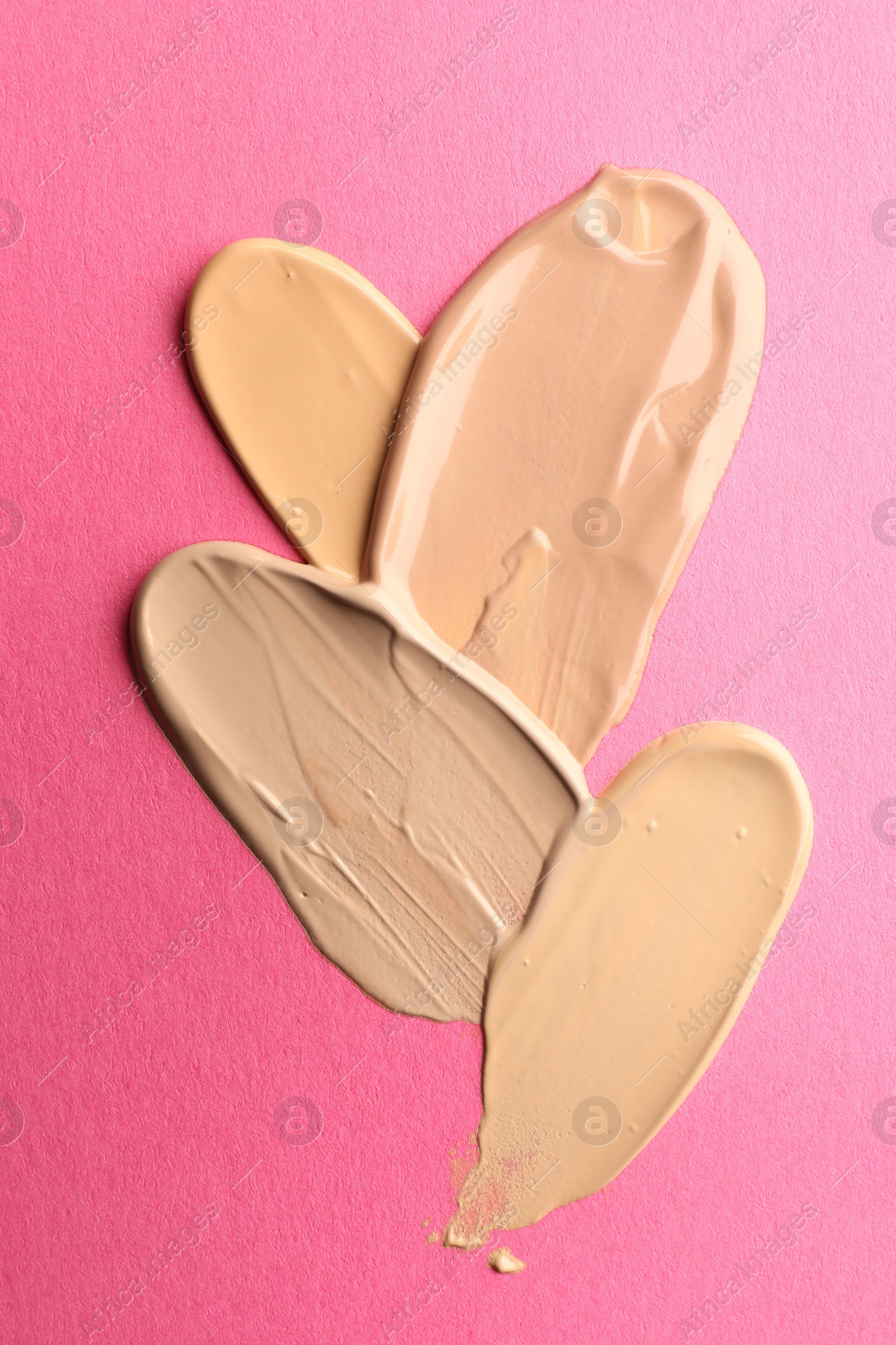 Photo of Foundation on pink background, top view. Smears of cosmetic product