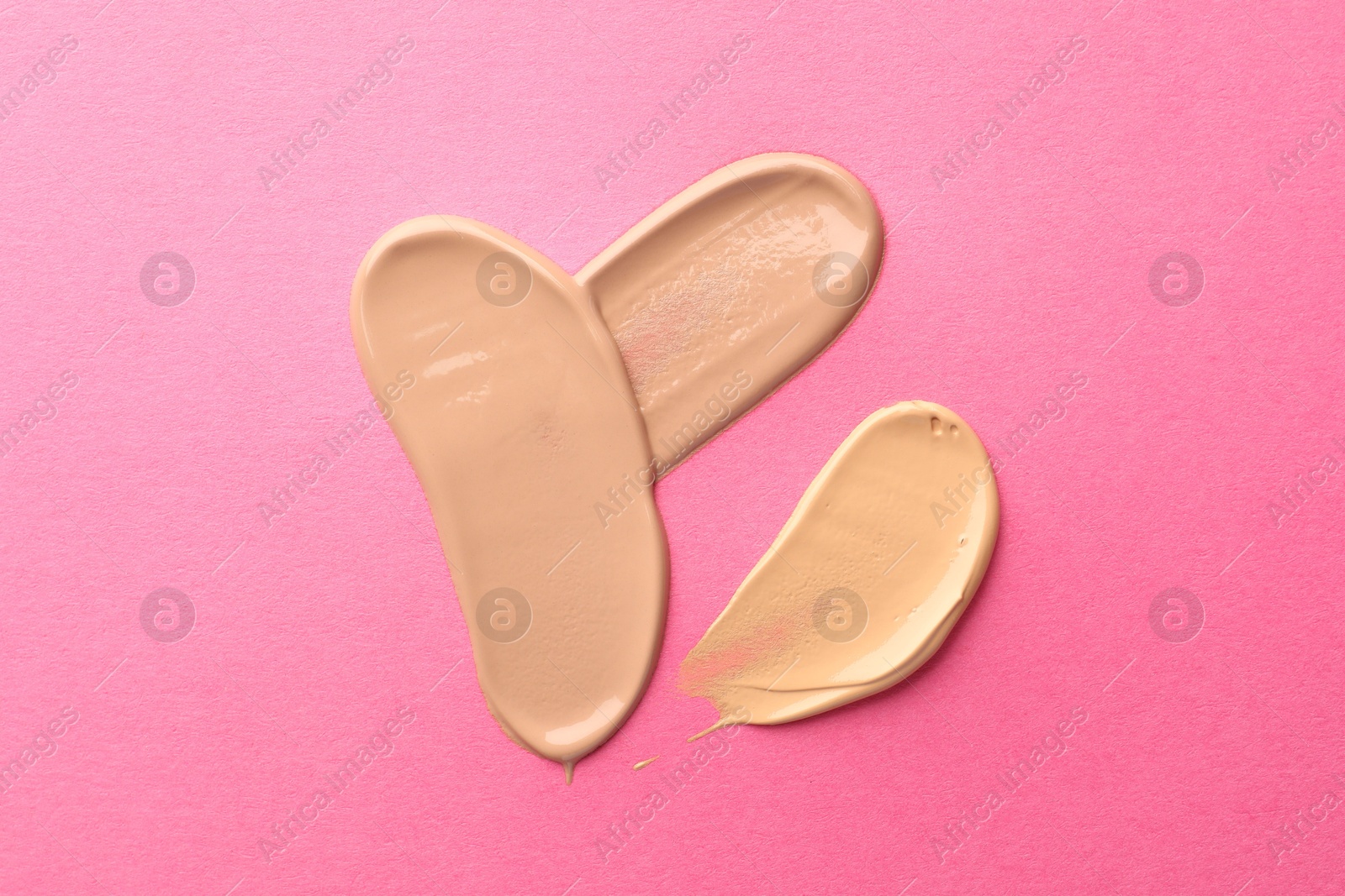 Photo of Foundation on pink background, top view. Smears of cosmetic product