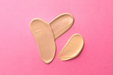 Photo of Foundation on pink background, top view. Smears of cosmetic product