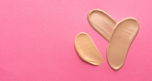 Photo of Foundation on pink background, top view with space for text. Smears of cosmetic product