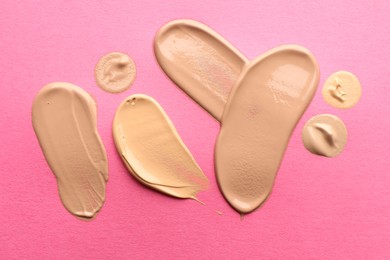 Photo of Foundation on pink background, top view. Smears of cosmetic product