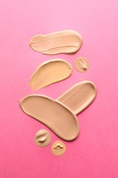 Photo of Foundation on pink background, top view. Smears of cosmetic product