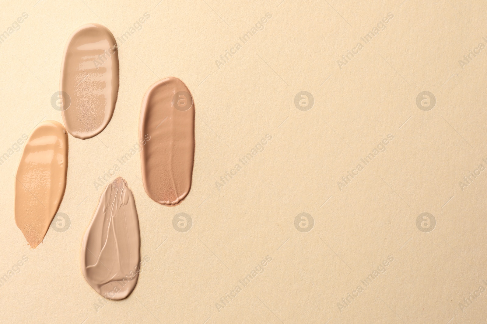 Photo of Samples of different foundations on beige background, top view. Space for text