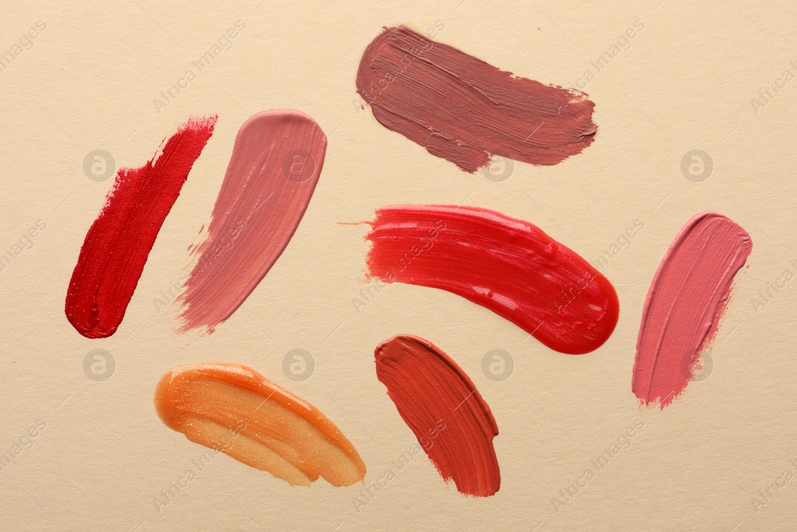 Photo of Samples of different lip products on beige background, top view