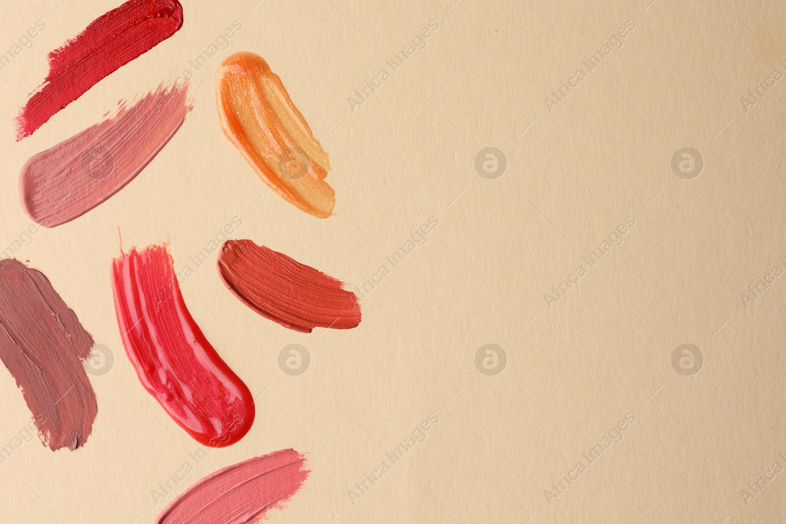 Photo of Samples of different lip products on beige background, top view. Space for text