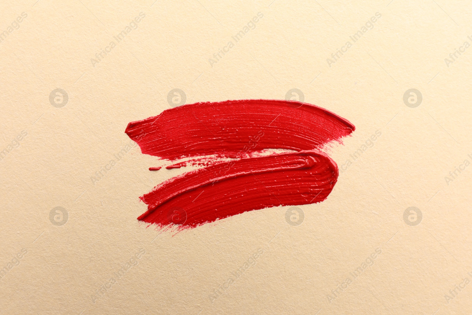 Photo of Red lipstick on beige background, top view. Smears of cosmetic product