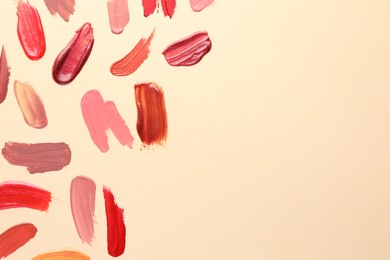 Photo of Samples of different lip products on beige background, top view. Space for text