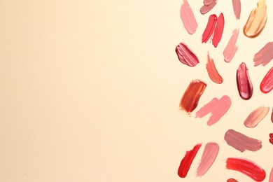 Photo of Samples of different lip products on beige background, top view. Space for text