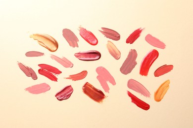 Photo of Samples of different lip products on beige background, top view