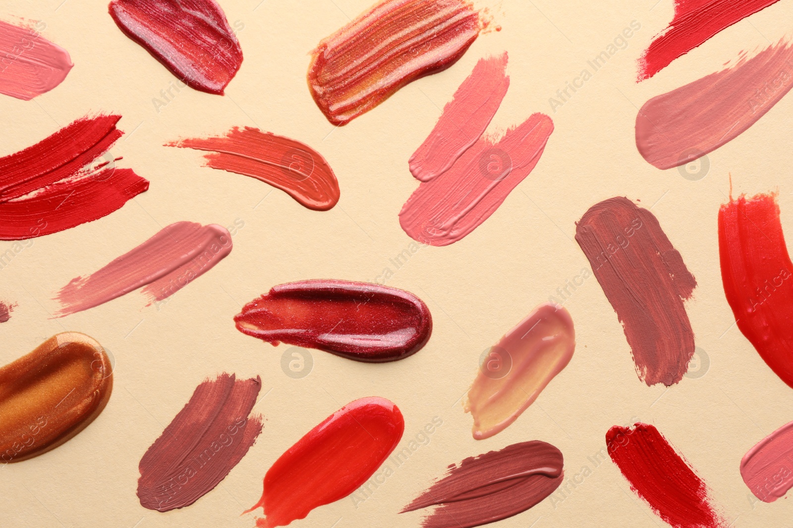 Photo of Samples of different lip products on beige background, top view