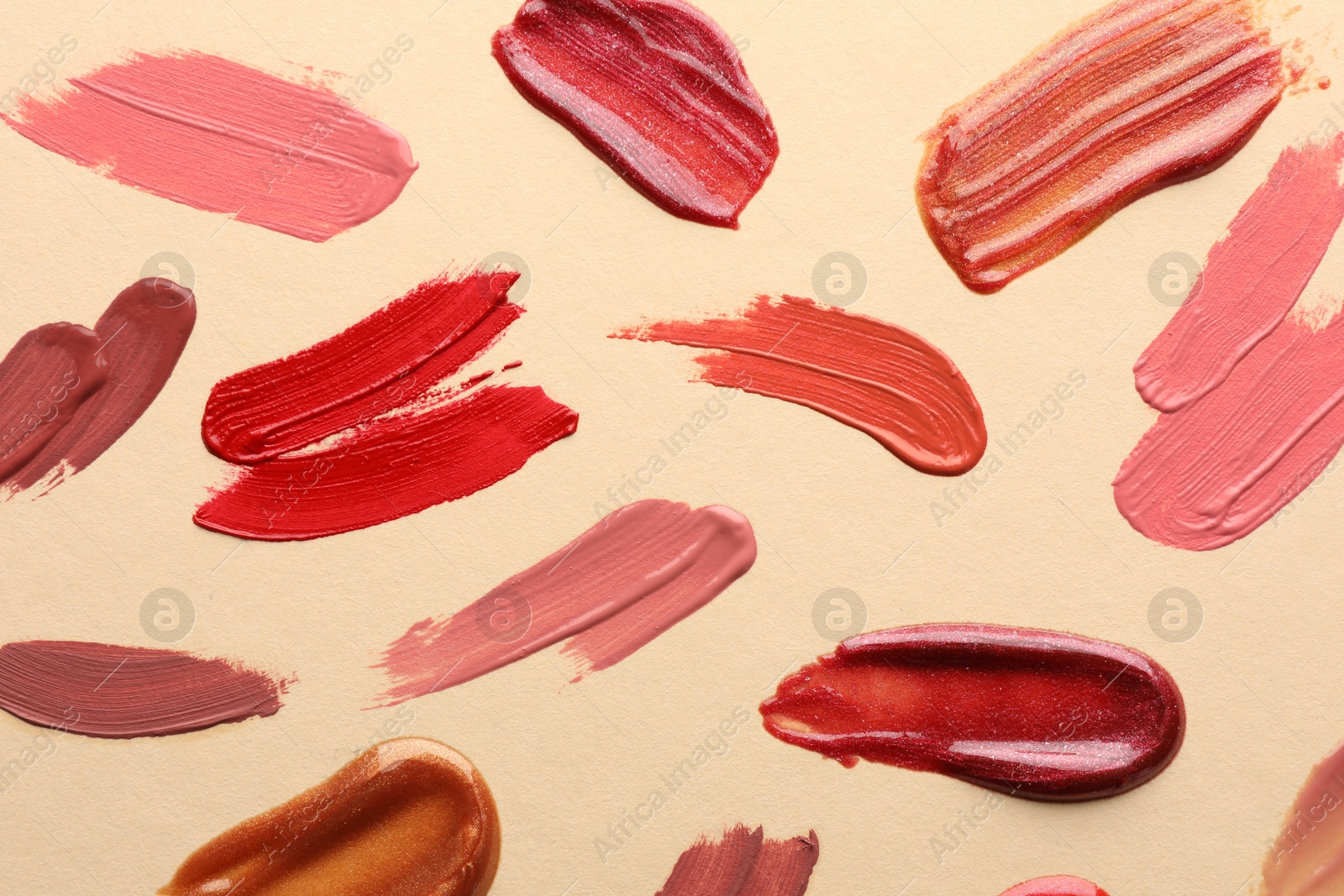 Photo of Samples of different lip products on beige background, top view