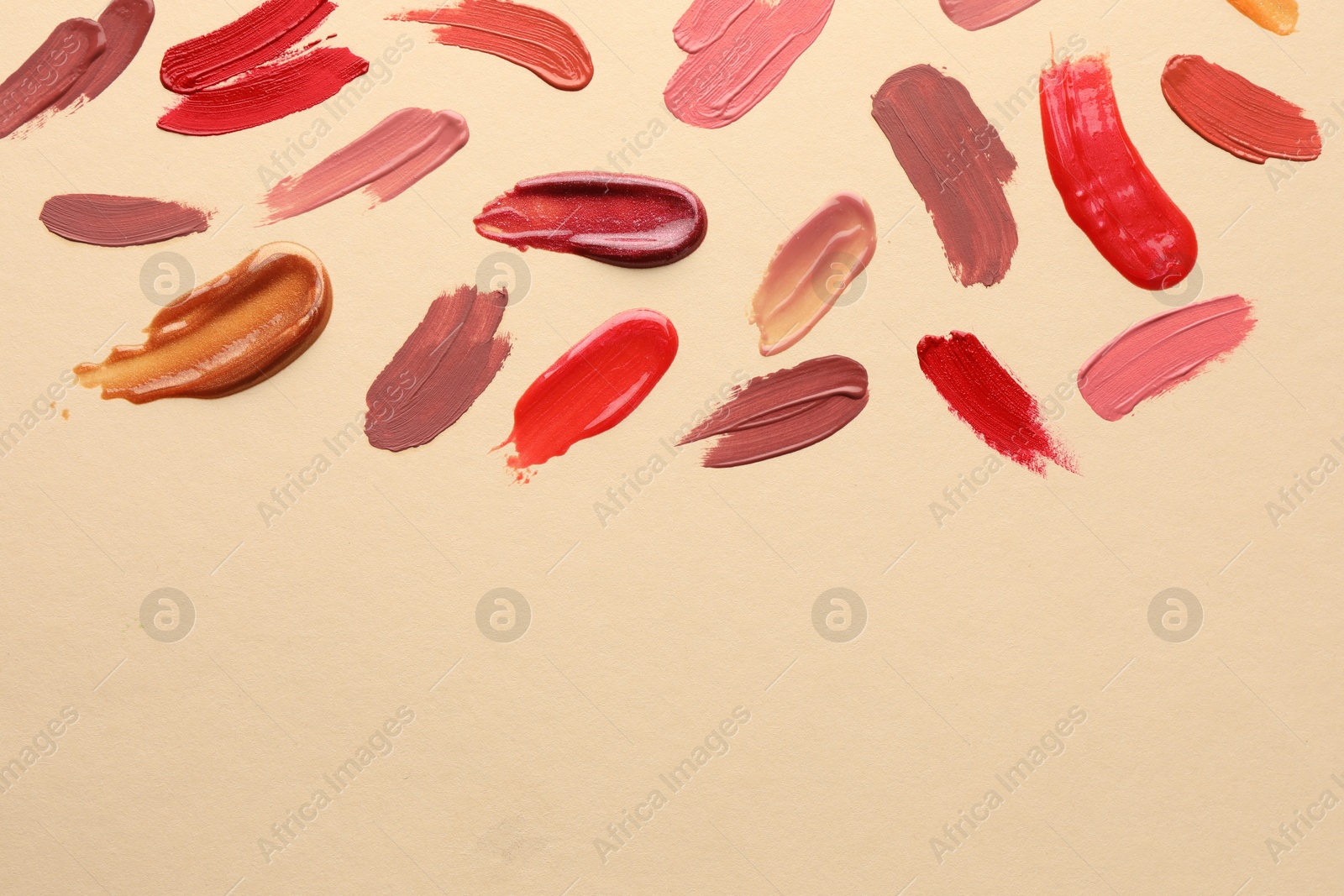 Photo of Samples of different lip products on beige background, top view. Space for text