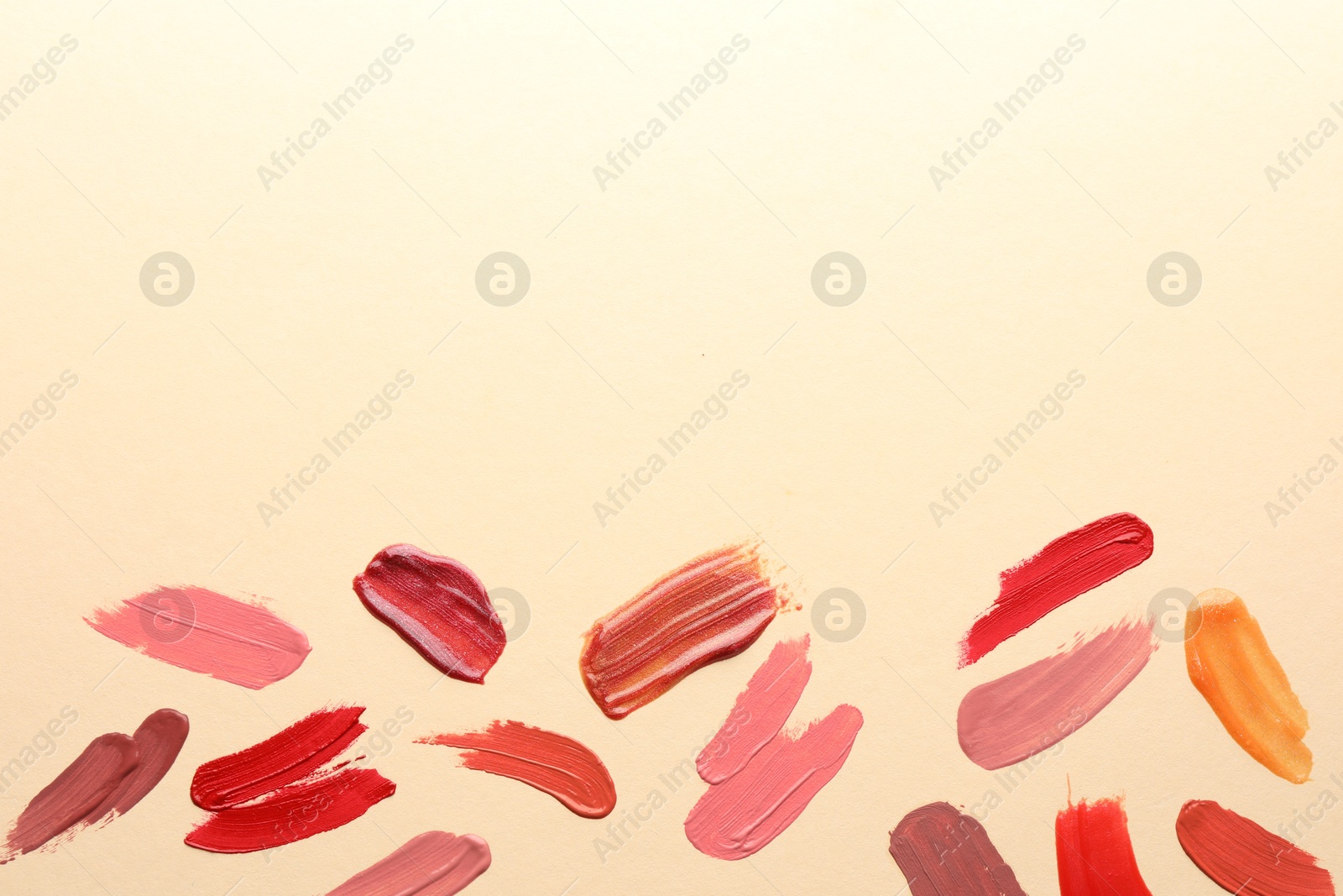 Photo of Samples of different lip products on beige background, top view. Space for text