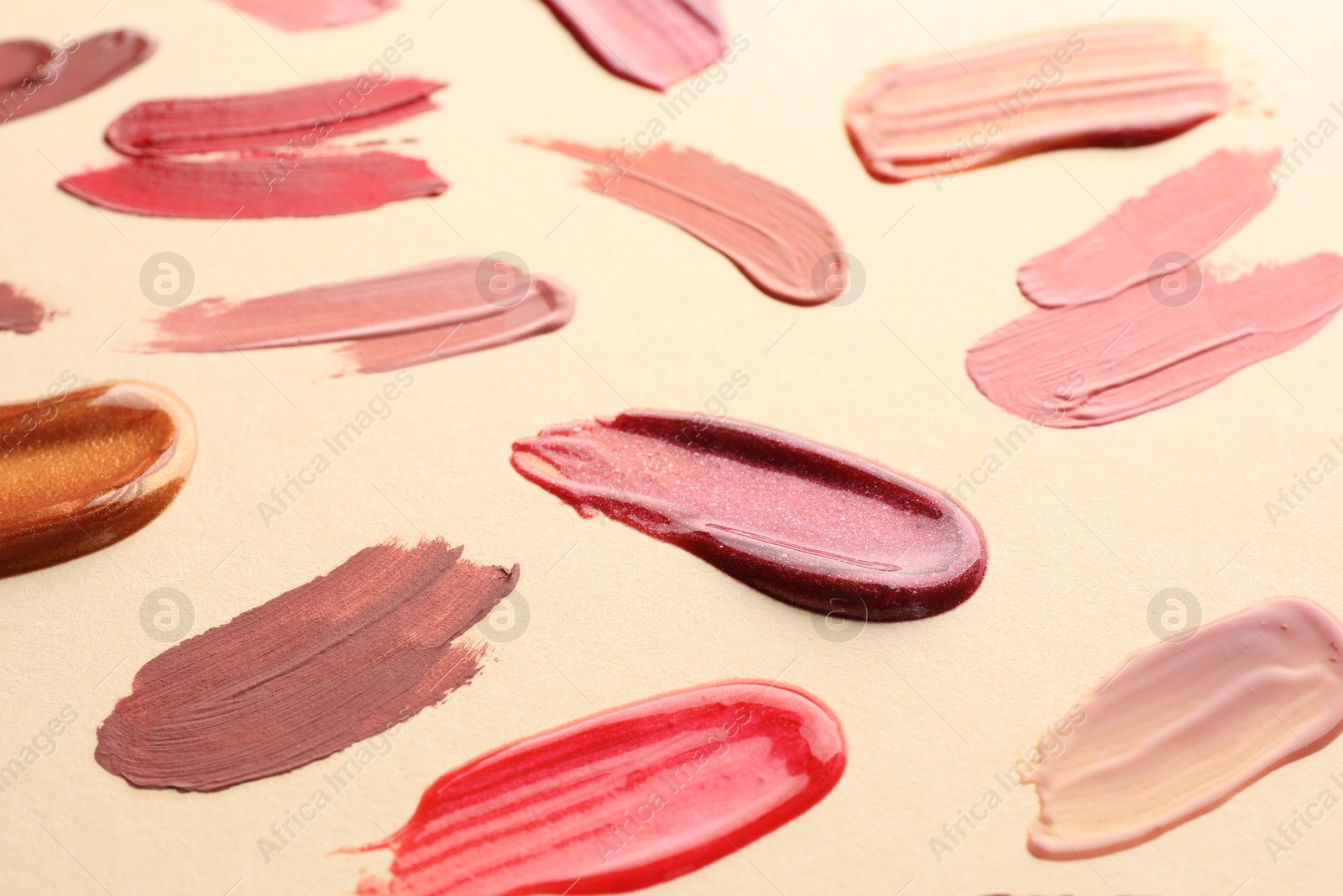 Photo of Samples of different lip products on beige background, closeup