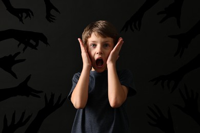 Teraphobia - fear of monsters. Scared boy screaming on black background. Silhouettes of creepy hands near him