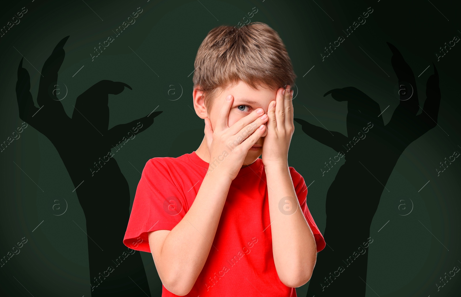 Image of Teraphobia - fear of monsters. Scared boy covering his eyes on dark background. Silhouette of creepy hands right behind child