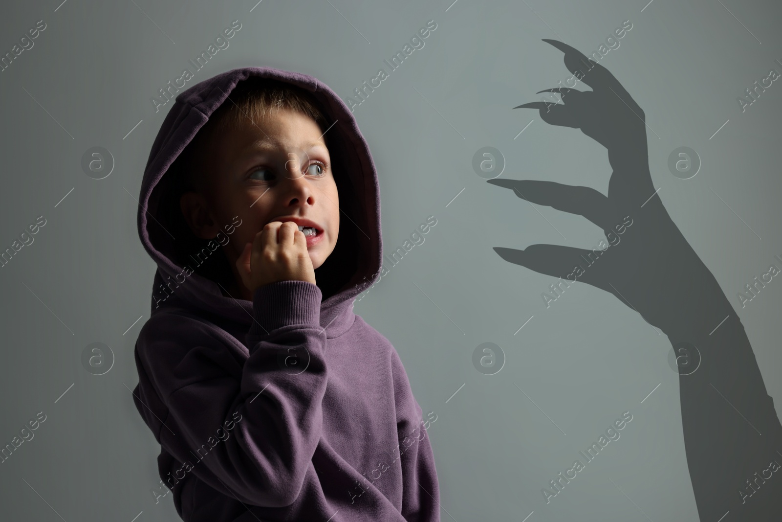 Image of Teraphobia - fear of monsters. Scared boy looking at creepy hand. Grey background