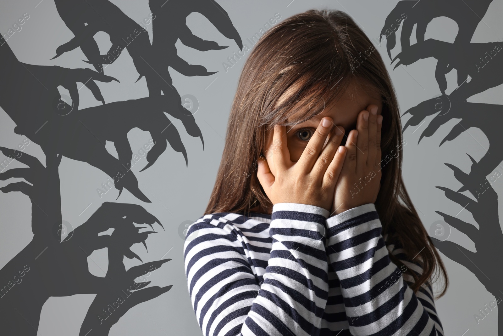 Image of Teraphobia - fear of monsters. Scared girl covering her eyes on grey background. Silhouette of creepy hands behind child