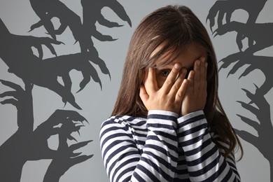 Image of Teraphobia - fear of monsters. Scared girl covering her eyes on grey background. Silhouette of creepy hands behind child