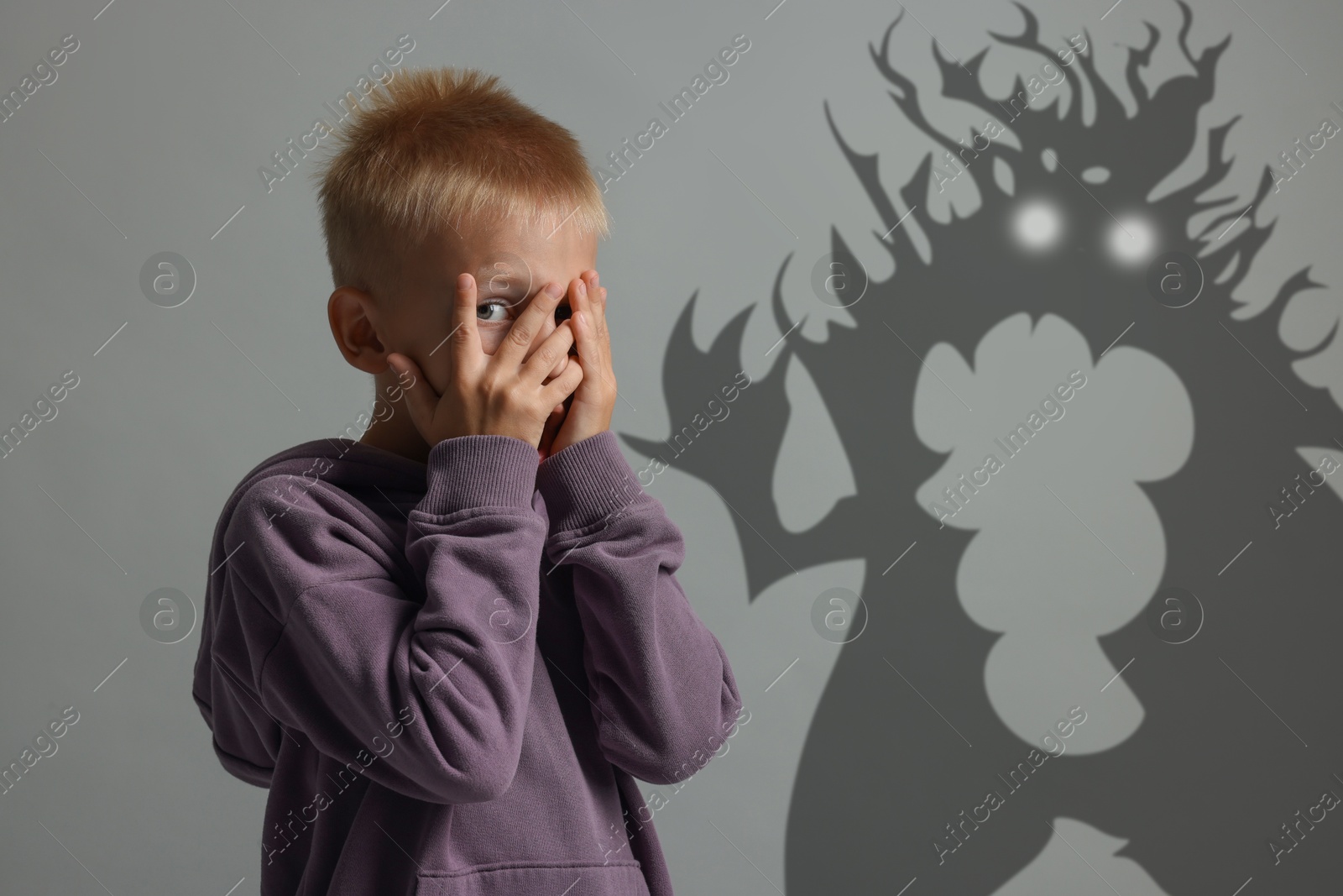 Illustration of Frightened by monsters, boy covering his eyes, teraphobia. Creepy shadows behind him