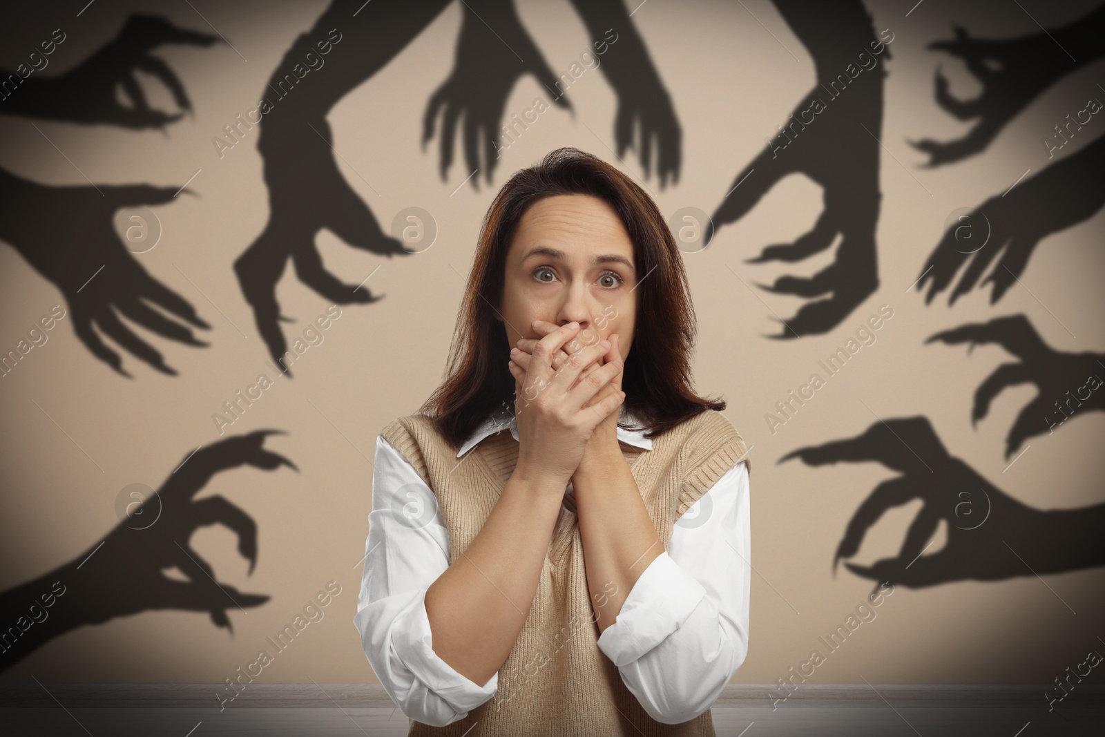 Image of Woman scared by monstrous hands reaching for her. Creepy shadows in room