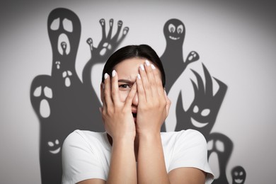 Image of Woman scared by monsters. Scary shadows on white wall