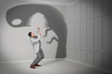 Businessman scared by monster. Scary shadow in room