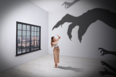 Image of Woman scared by monstrous hands reaching for her. Creepy shadows in room