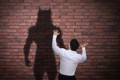 Image of Man scared by monster. Scary shadow on brick wall