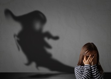 Image of Little kid scared by monster. Spooky shadow in room