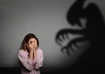 Image of Woman scared by monster. Scary shadow in room