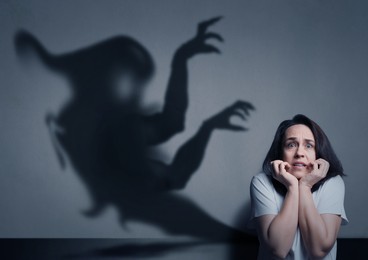 Image of Woman scared by monster. Scary shadow in room