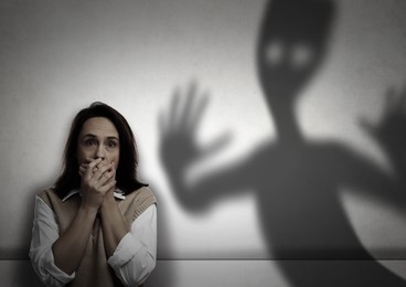 Image of Woman scared by monster. Scary shadow in room